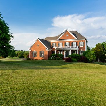 Red brick colonial house with white trim and arched portico