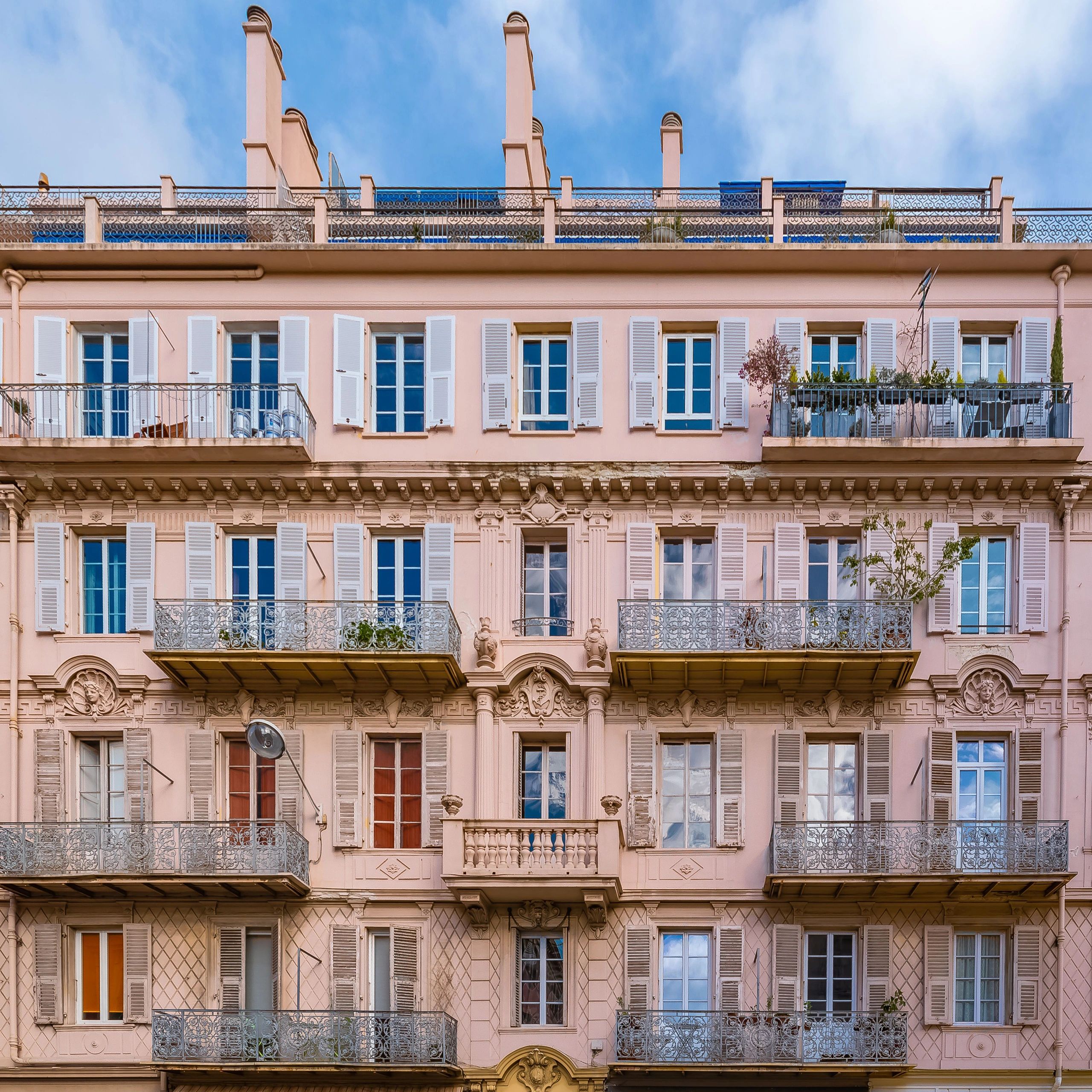 Parisian Haussmann apartment building with pink stone balconies